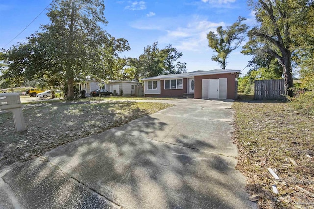 ranch-style house featuring driveway, fence, and a front yard