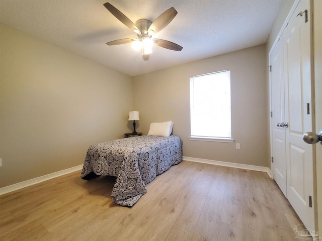 bedroom featuring ceiling fan, light hardwood / wood-style floors, and a textured ceiling