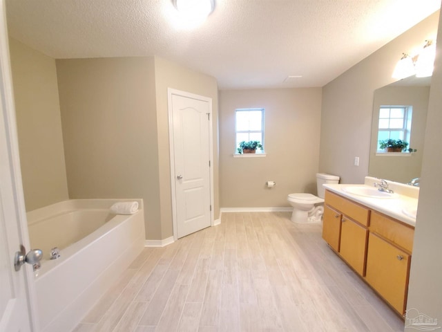 bathroom featuring a wealth of natural light, wood-type flooring, and a textured ceiling