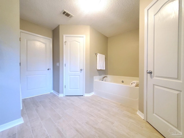 bathroom featuring a bath, wood-type flooring, and a textured ceiling