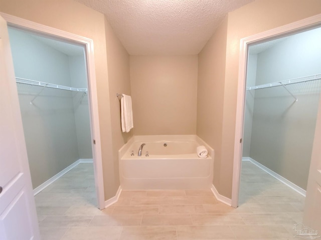 bathroom with a washtub and a textured ceiling