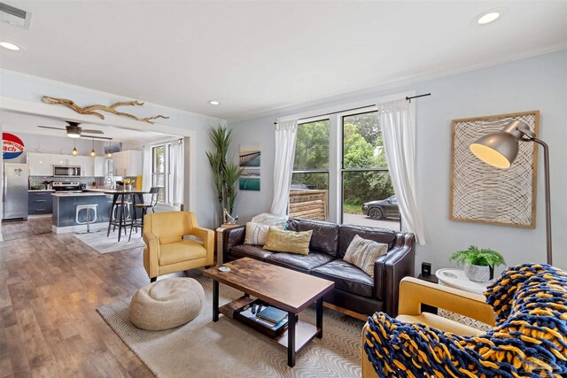 living room featuring ceiling fan, light hardwood / wood-style flooring, and crown molding