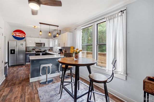 dining area with ceiling fan, crown molding, dark wood-type flooring, and sink