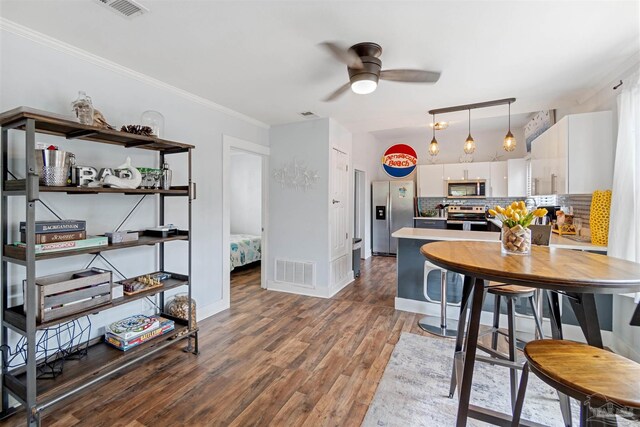 kitchen featuring backsplash, stainless steel appliances, white cabinets, ceiling fan, and hardwood / wood-style flooring