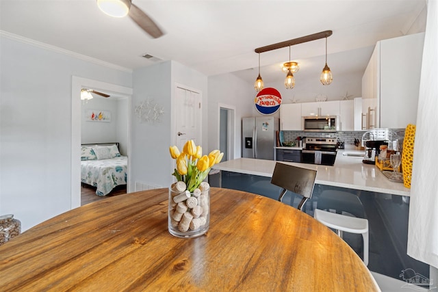 dining area with sink, ceiling fan, crown molding, and wood-type flooring