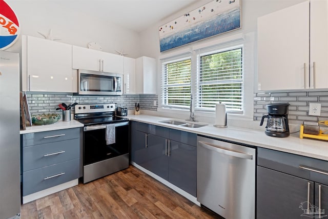 kitchen featuring dark wood-type flooring, a sink, white cabinets, light countertops, and appliances with stainless steel finishes