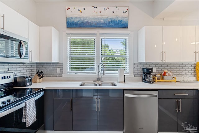 kitchen featuring white cabinets, modern cabinets, stainless steel appliances, light countertops, and a sink