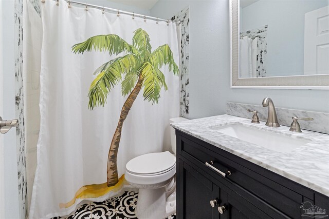 bathroom featuring tile patterned flooring, vanity, walk in shower, and toilet