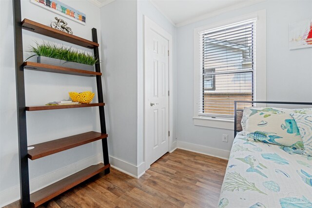 bedroom with multiple windows, ornamental molding, and hardwood / wood-style flooring