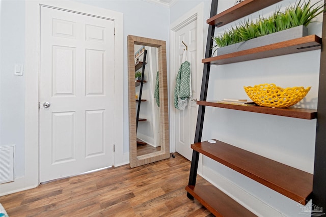 corridor with visible vents, crown molding, and wood finished floors