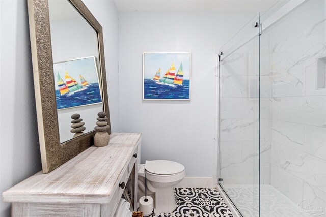 bathroom featuring a shower with shower door, toilet, vanity, and tile patterned floors