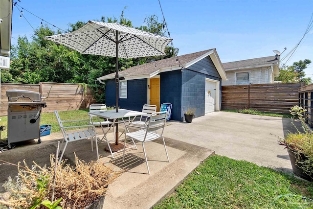 view of patio featuring outdoor dining area, a garage, an outdoor structure, driveway, and grilling area