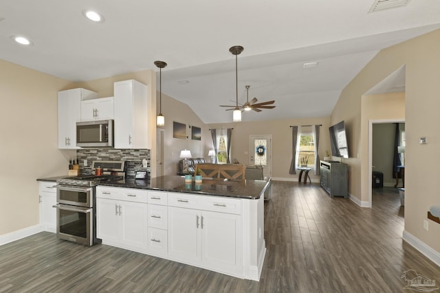 kitchen featuring lofted ceiling, white cabinets, decorative backsplash, hanging light fixtures, and stainless steel appliances