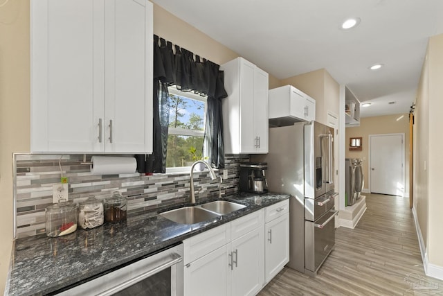 kitchen with dark stone countertops, sink, independent washer and dryer, and white cabinets