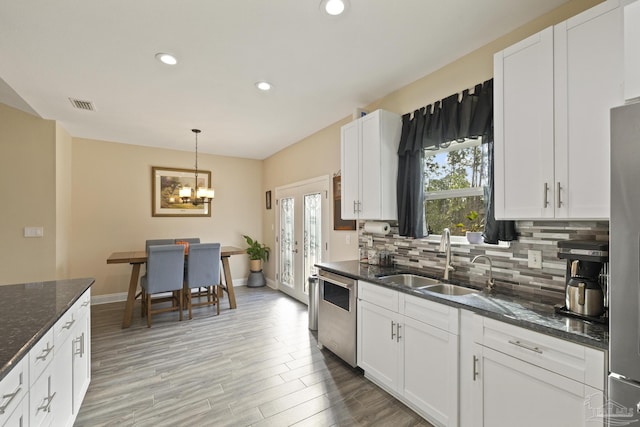 kitchen featuring stainless steel appliances, sink, white cabinets, and dark stone counters