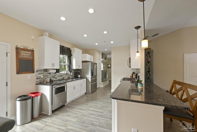 kitchen featuring stainless steel appliances, hanging light fixtures, white cabinets, and washer / clothes dryer