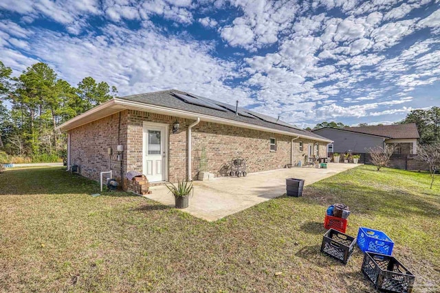 rear view of house featuring a patio area, solar panels, and a lawn