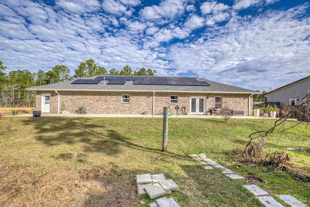 back of house with a yard, a patio area, and solar panels