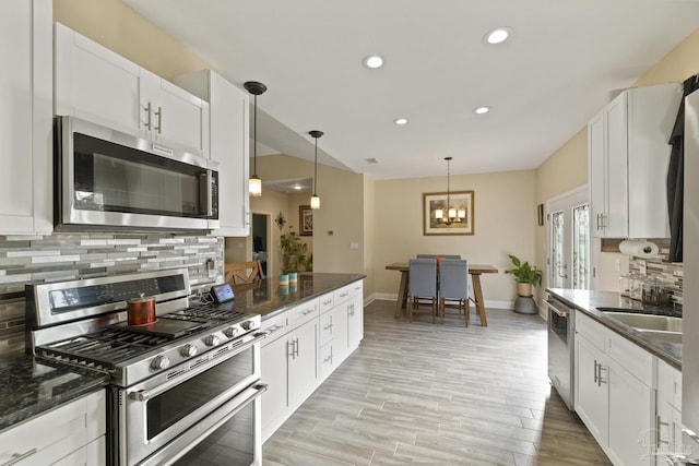 kitchen with white cabinetry, hanging light fixtures, and appliances with stainless steel finishes