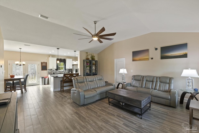 living room with dark wood-type flooring, ceiling fan with notable chandelier, and vaulted ceiling