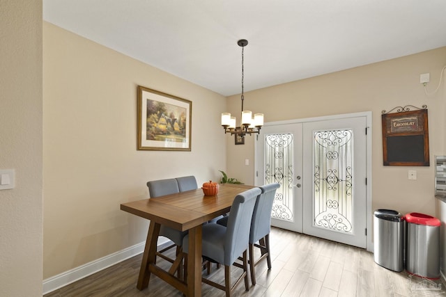 dining room with french doors, a chandelier, and light hardwood / wood-style floors