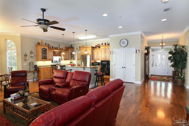 living room featuring visible vents, ornamental molding, baseboards, dark wood-style floors, and ceiling fan with notable chandelier