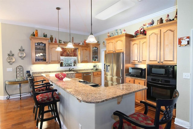kitchen with a kitchen breakfast bar, a center island, ornamental molding, glass insert cabinets, and black appliances