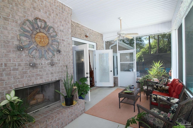 sunroom with a ceiling fan and a brick fireplace