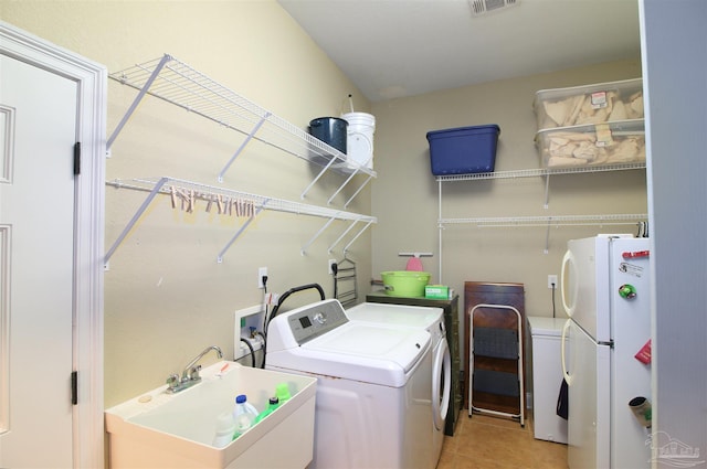 laundry room with laundry area, visible vents, light tile patterned flooring, washing machine and clothes dryer, and a sink