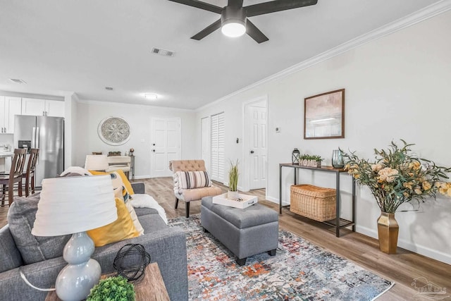 living room featuring crown molding, ceiling fan, and hardwood / wood-style flooring