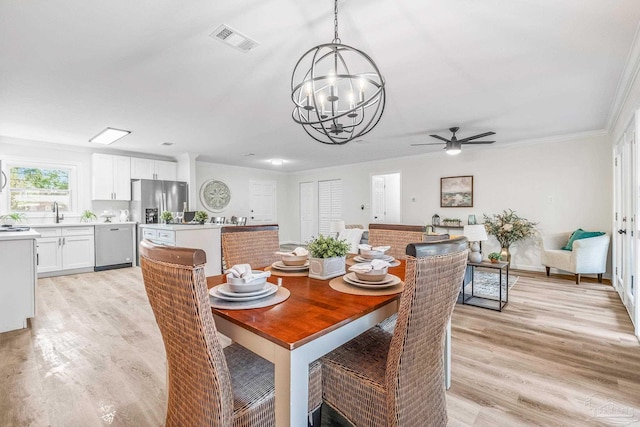 dining room with ceiling fan with notable chandelier, light hardwood / wood-style floors, sink, and crown molding