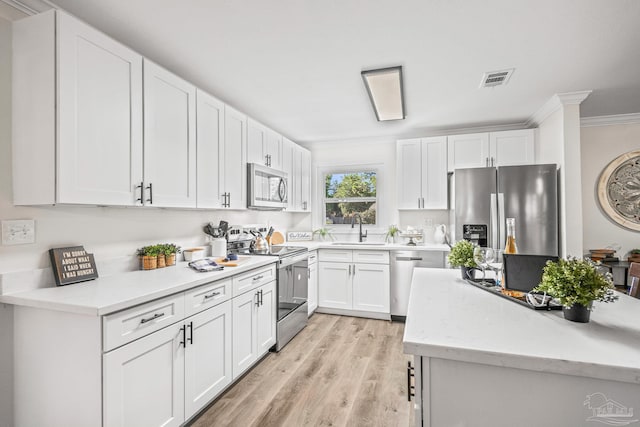 kitchen featuring ornamental molding, stainless steel appliances, sink, light hardwood / wood-style floors, and white cabinetry