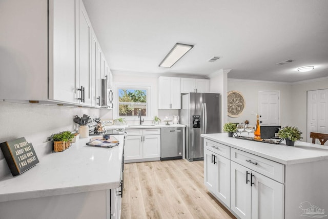 kitchen with ornamental molding, stainless steel appliances, sink, light hardwood / wood-style flooring, and white cabinetry