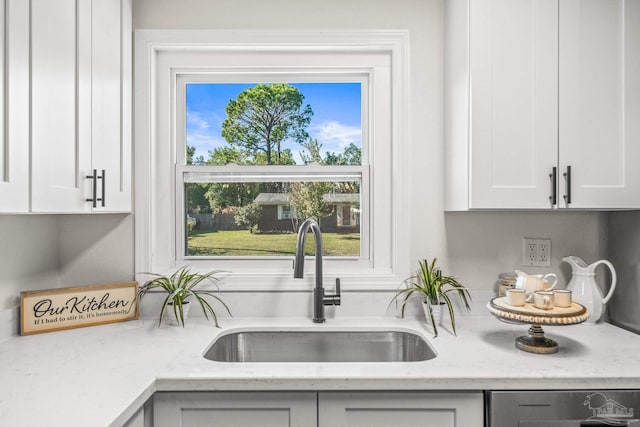 kitchen with white cabinets, light stone counters, and sink