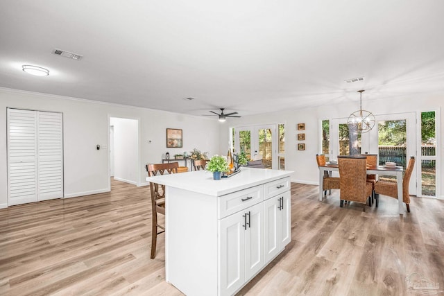 kitchen with a center island, french doors, white cabinets, decorative light fixtures, and light hardwood / wood-style floors