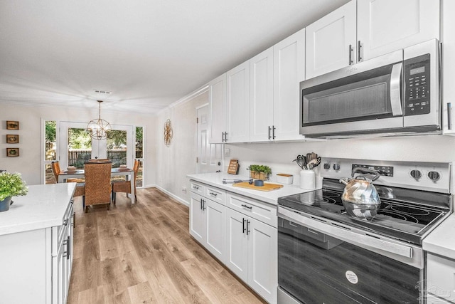 kitchen featuring white cabinets, crown molding, hanging light fixtures, appliances with stainless steel finishes, and a chandelier