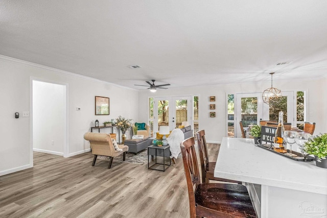 dining room featuring french doors, light hardwood / wood-style floors, plenty of natural light, and crown molding