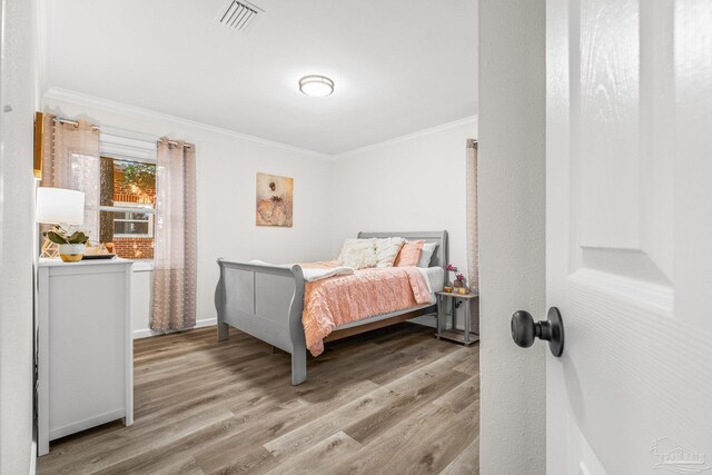 bedroom with light hardwood / wood-style floors and crown molding