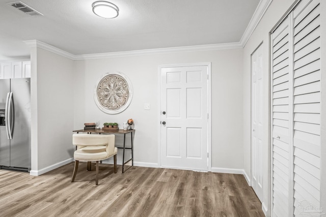 foyer with crown molding and light wood-type flooring