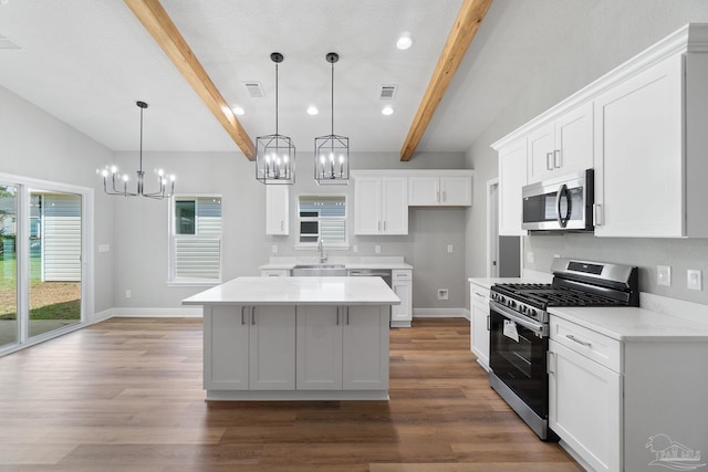 kitchen featuring a kitchen island, appliances with stainless steel finishes, white cabinetry, sink, and hanging light fixtures