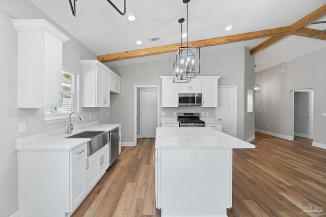 kitchen featuring a kitchen island, white cabinetry, sink, hanging light fixtures, and stainless steel appliances