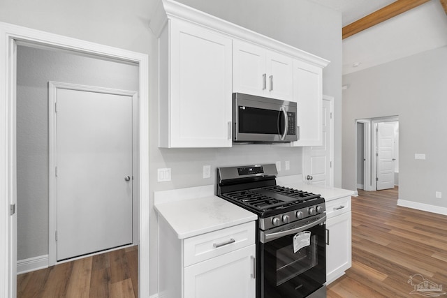 kitchen with appliances with stainless steel finishes, dark wood-type flooring, and white cabinets