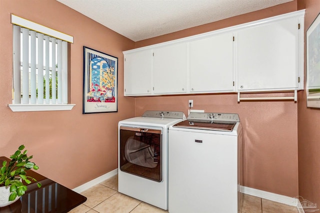 laundry area with cabinets, a textured ceiling, light tile patterned floors, and separate washer and dryer