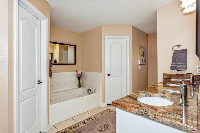 bathroom featuring vanity, tile patterned flooring, a textured ceiling, and a tub to relax in