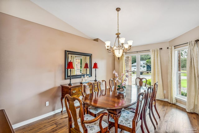 dining room with wood-type flooring, an inviting chandelier, and vaulted ceiling