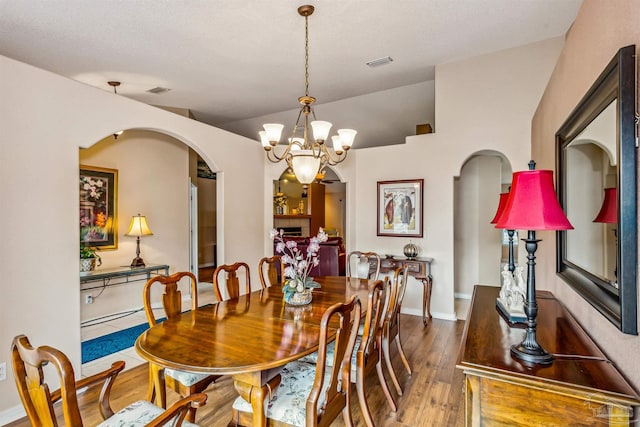 dining area with dark hardwood / wood-style flooring, a textured ceiling, a tile fireplace, and an inviting chandelier