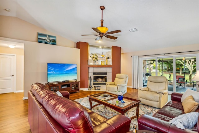 living room featuring a fireplace, light hardwood / wood-style floors, ceiling fan, and lofted ceiling