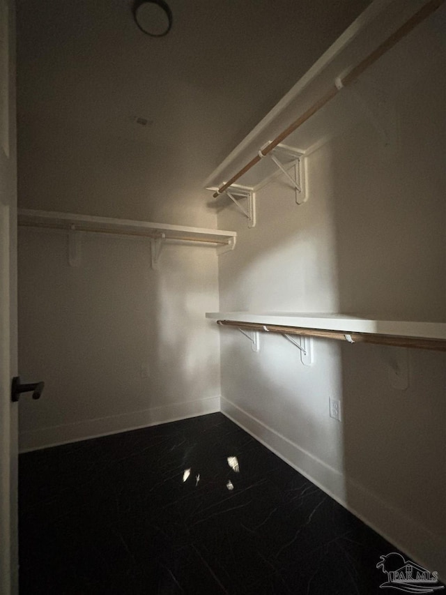 walk in closet featuring marble finish floor