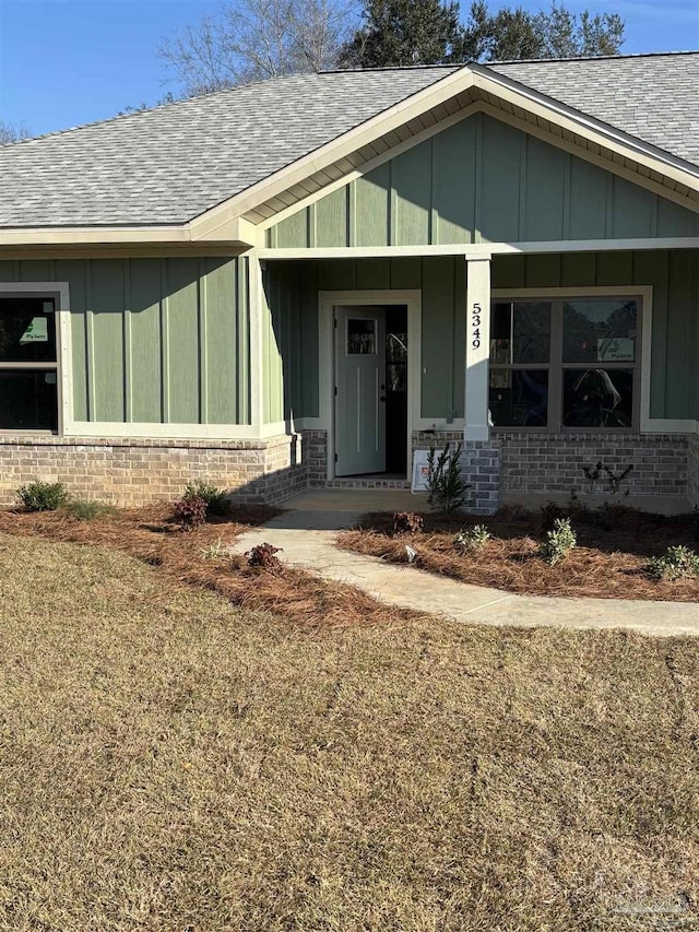 entrance to property with board and batten siding, brick siding, and a shingled roof