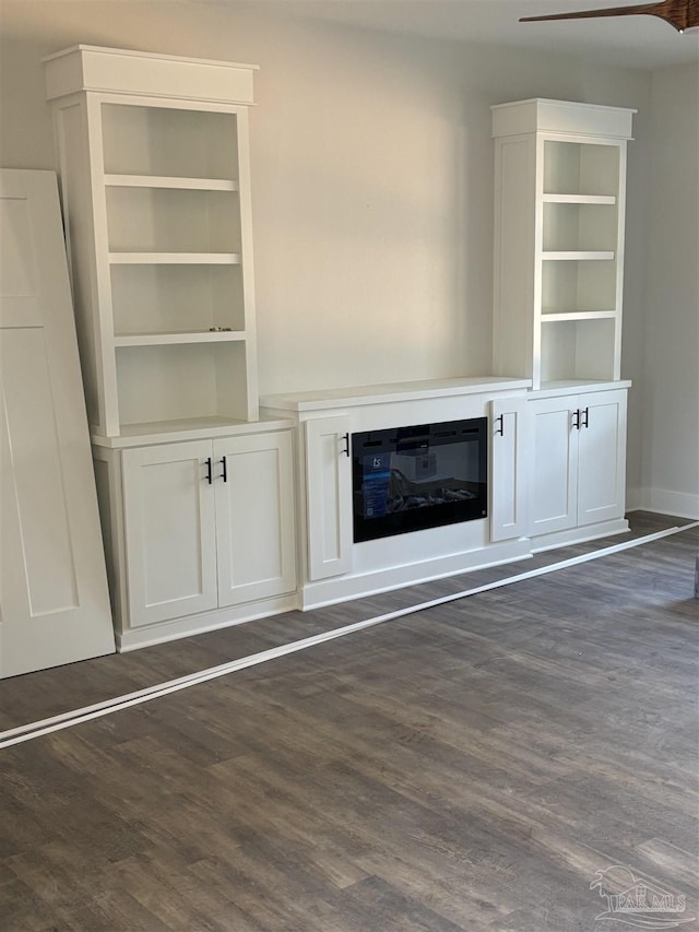 unfurnished living room featuring dark wood-style flooring and a glass covered fireplace